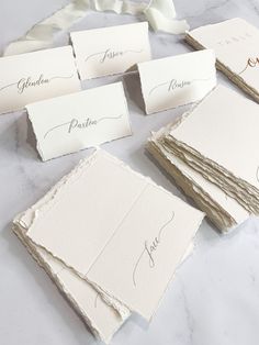 wedding place cards laid out on top of each other, with the name written on them