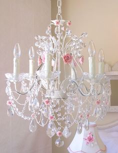 a white chandelier with pink flowers and candles