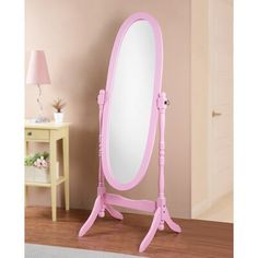 a pink mirror sitting on top of a wooden floor next to a table and chair