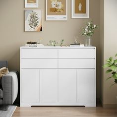 a living room with white furniture and pictures on the wall above it's dresser