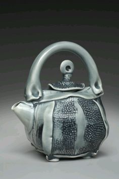 a teapot with a handle on it sitting in front of a gray background,