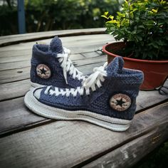 a pair of blue sneakers sitting on top of a wooden table next to a potted plant