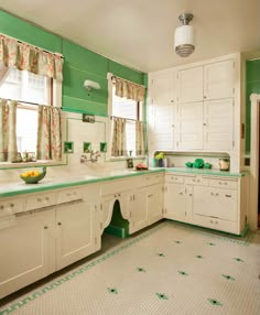 a green and white kitchen with lots of counter space, sink, and cabinets in it