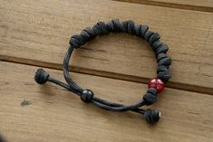 This stunning accessory is designed to help you stay close to our Lord while wearing your faith on your sleeve. Crafted with durable, premium paracord rope in a sleek black/gray color, this adjustable bracelet features 10 knots that represent the 10 Hail Mary prayers. But what truly sets it apart is its unique milky red Our Father bead, reminiscent of the fiery passion and devotion required to vanquish the forces of darkness. Wear this bracelet as a powerful reminder of your commitment to prayer Adjustable Black Braided Bracelet, Black Outdoor Bracelet Jewelry, Black Bracelet Jewelry For Outdoor, Casual Everyday Braided Bracelet With Black Band, Casual Black Braided Bracelets For Friendship, Casual Black Braided Friendship Bracelets, Durable Black Braided Bracelets As Gift, Durable Black Braided Bracelet As Gift, Durable Black Braided Bracelet Gift