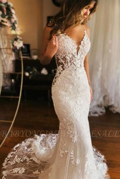 a woman in a white wedding dress standing on a wooden floor with her back to the camera