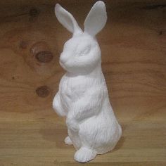 a white rabbit statue sitting on top of a wooden table