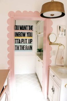 a bathroom with pink walls and white cabinets in the doorway to it's bath room