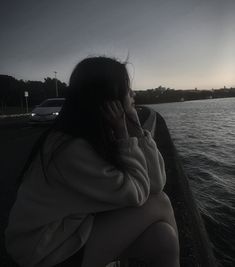 a woman sitting on the side of a boat talking on a cell phone