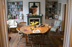 a dining room table and chairs in front of a fire place with bookshelves