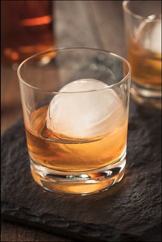 two glasses filled with ice on top of a wooden table