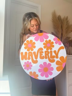 a woman holding a sign that says waverly in orange and pink flowers on it