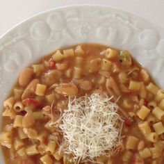 a white bowl filled with pasta and cheese on top of a table next to a fork