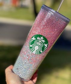 a person holding up a pink starbucks cup with glitter on the lid and straw in their hand