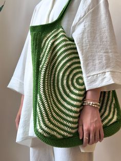 a woman holding a green and white bag with a spiral design on the front pocket