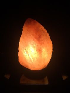 a large orange rock sitting on top of a black table next to a light bulb