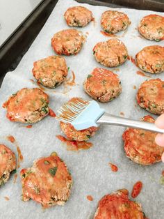 someone is using a spatula to spread sauce on some hamburger pattie patties