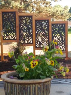 a potted plant with yellow and purple flowers in front of a wooden privacy panel