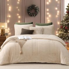 a bedroom with christmas lights on the wall and a bed covered in white comforter