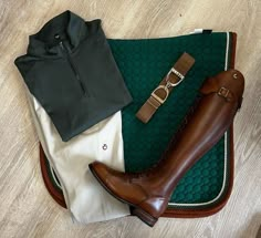 a pair of brown boots sitting on top of a green rug next to a black shirt