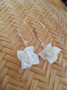 two white flowers are sitting on top of some silver wire earwires that have been folded into the shape of flower petals