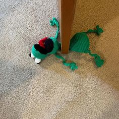 a crocheted green dragon laying on the floor next to a door