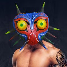 a man wearing a red and blue mask with spikes on it's head is looking at the camera