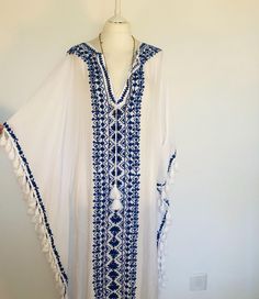 A Beautiful Boho Kaftan,Maxi Dress ,Cover Up. Long and Embroidered and Floaty,Perfect for Poolside,Beach holidays or Parties.  In Fresh White Cotton Viscose Mix,with a Lovely Traditional Indigo Blue Embroidery and Tassels. This dress flows loosely with a V neckline and a softly draped silhouette. This dress is really versatile for Holidays , lunches , special events and celebrations. It feels loose and floaty to wear , and easy ro roll up to take away. One Size S M L XL. UK 10 to 20   US 6 to 16 Flowy Beach Dress For Festivals, Traditional White Kaftan With Tassels, V-neck Dresses For Vacation Festivals, Traditional Vacation Maxi Dress With Tassels, Bohemian Tasseled Kaftan For Festivals, Bohemian Tassel Kaftan For Festivals, Bohemian Kaftan With Tassels For Festivals, Long Embroidered Cover-up For Vacation, Embroidered Boho Maxi Dress For Summer