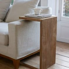 a white couch sitting next to a table with a coffee cup on top of it