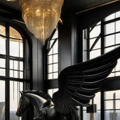 a statue of a horse with wings on it's back in front of large windows