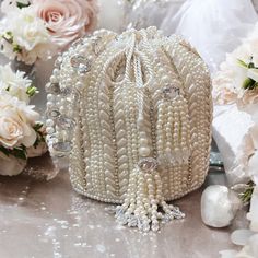 Introducing our exquisite Bridal Potli Bag in Ivory, a perfect accessory for your wedding day. Crafted from luxurious raw silk, this potli bag embodies elegance and sophistication. The delicate beadwork and sparkling crystal embellishments adorn the bag, adding a touch of opulence and grace. The bag features a stunning handmade handle, intricately embellished with beads and crystals, offering both beauty and functionality. Designed to complement your bridal attire, this potli bag is the ideal choice to carry your essentials in style. Let this timeless piece add a final touch of luxury to your special day. Evening Cream Potli Bag, Pearl White Evening Bag With Pearl Handle For Wedding, Pearl White Wedding Clutch With Pearl Handle, Beige Pearl Embellished Evening Bag For Wedding, Luxury Potli Bag With Pearl Embroidery, Elegant Cream Potli Bag For Wedding, Elegant Cream Potli Bag For Party, Cream Pearl Embroidered Potli Bag For Parties, Elegant Cream Potli Bag In Pouch Shape