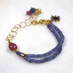 Glittering, vibrantly hued genuine polished natural periwinkle hued tanzanite, one of the rarest and most prized of all gemstones, sparkles on this strand in a beautiful bright striking splash of color! A plump faceted pink sapphire accents the side of the wrist. 14k gold fill chain and colorful drop embellishments add a little chic bling. l Blue Tanzanite Gemstone Bracelets, Handmade Blue Amethyst Bracelets, Blue Tanzanite Bracelet Jewelry, Blue Amethyst Bracelets With Natural Stones, Blue Amethyst Gemstone Bracelet, Blue Tanzanite Bracelet, Multi Gemstone Bracelet, Tanzanite Bracelet, Carnelian Bracelet