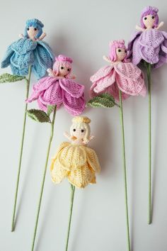 three crocheted dolls sitting on top of flower stems with one doll in the middle