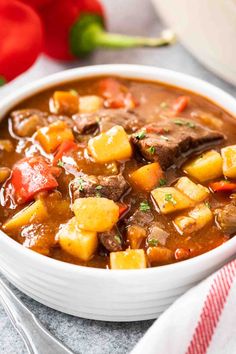 a white bowl filled with beef and potatoes