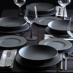 the table is set with black plates and silverware