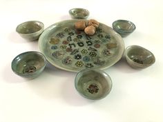 an assortment of ceramic bowls and cups are arranged in a circular arrangement on a white surface