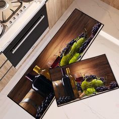 two pictures of wine bottles and grapes are on the kitchen counter next to the stove