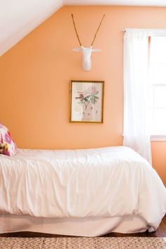 a bedroom with an orange wall and white bed