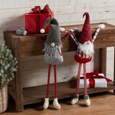 two gnomes are standing next to each other on a wooden bench with presents in the background