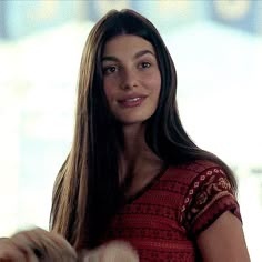 a woman with long hair holding a white cat in her hand and smiling at the camera