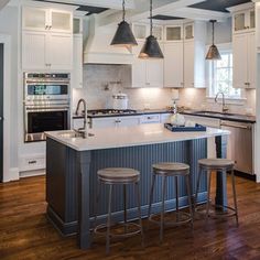 a kitchen with an island and three stools in front of the stove top oven