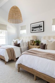 two beds in a bedroom with white linens and tan blankets on top of them