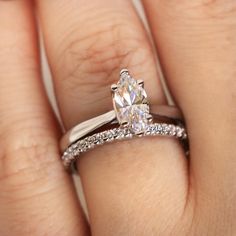 a woman's hand with a diamond ring on top of her finger and an engagement band