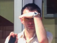 a man wearing sunglasses and holding his hand to his forehead