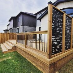 a wooden deck in front of some black and white houses with grass on the ground