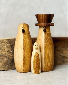 two wooden penguins are standing next to each other in front of a piece of wood