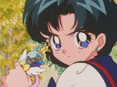 an anime character with blue eyes and black hair holding a small object in her hand