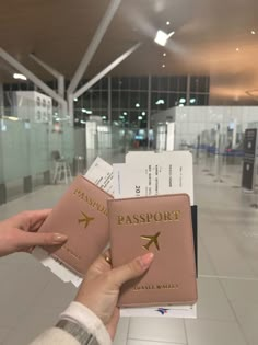 a person holding two passport cards in their hand at an airport terminal with the door open