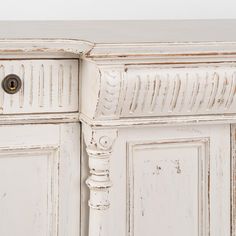 an old white painted cabinet with brass knobs