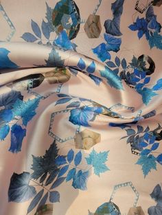 a blue and white floral print fabric with small leaves on the bottom, along with an insect - like design