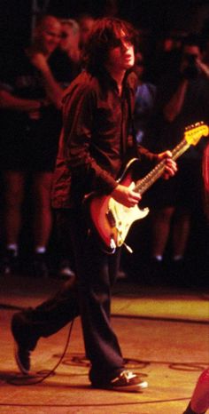 two young men playing guitars in front of a crowd